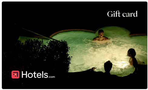 Three people enjoy a nighttime swim in a hotel pool. Text reads "Gift card" and "Hotels.com" on the image.